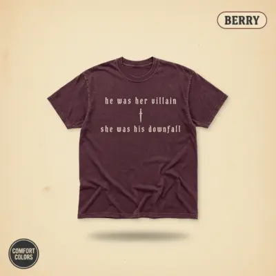 Berry garment-dyed Comfort Colors tee with dark romance phrase "He Was Her Villain She Was His Downfall" in serif typography, front chest print