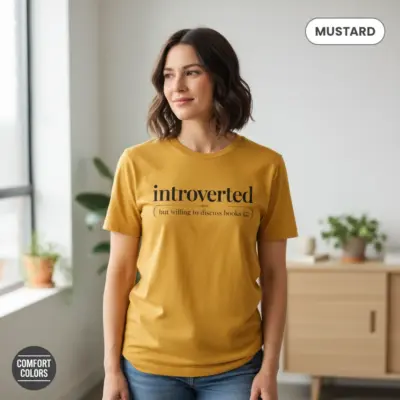 Mustard Comfort Colors garment-dyed tee with bold text phrase Introverted But Willing to Discuss Books worn by a reader indoors