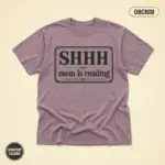 Orchid Comfort Colors garment-dyed t-shirt with bold Shhh Mom Is Reading typographic slogan – front studio view